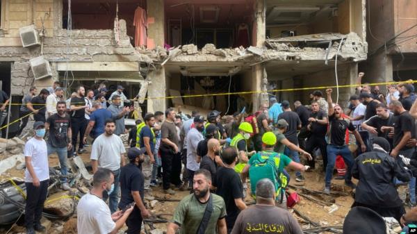 People gather near a damaged building at the scene of an Israeli missile strike in the southern suburbs of Beirut, Sept. 20, 2024.