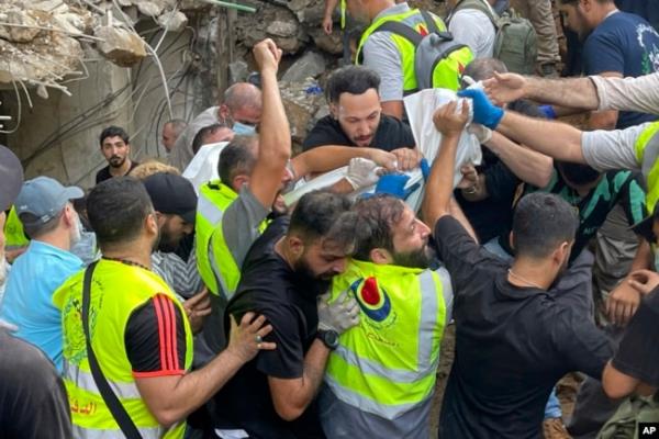 Rescuers carry a body at the scene of a missile strike in the southern suburbs of Beirut, Sept. 20, 2024.