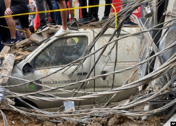 People stand on top of a damaged car at the scene of a missile strike in the southern suburbs of Beirut, Sept. 20, 2024.