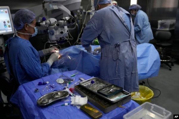 Elias Jaradeh, a legislator and an ophthalmologist, left, performs eye surgery on a man who was injured in the explosion of a handheld device, at a hospital in Beirut, Sept. 20, 2024.